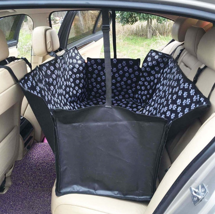 Car seat protector with black base and black paw-print side panels for rear seat.
