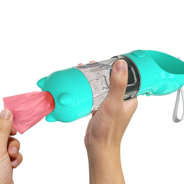 Turquoise portable dog water bottle with pink waste bag and transparent drinking chamber